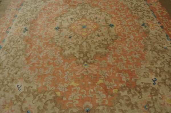 Ornate floral rug pattern in muted rust orange, tan, and brown with small blue and yellow details.