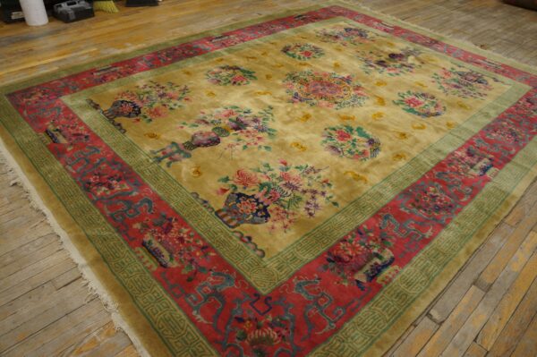 Plush gold rug featuring scattered floral vases and medallions, framed by red and teal borders on wood flooring.