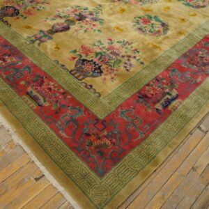 High-pile yellow rug displaying vibrant floral vases and a thick red and teal patterned border on rustic wood floors.