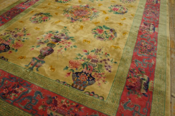 Angled view of a golden high-pile rug with colorful floral motifs and complex red and teal borders on wood floors.