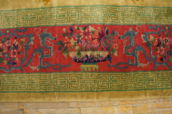 High-pile rug border featuring red and golden yellow bands, blue stylized motifs, and a central floral vase.