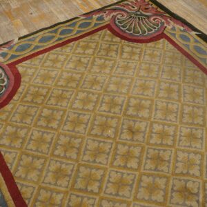 Yellow and gray patterned rug with ornate red and blue borders resting on distressed wooden planks.