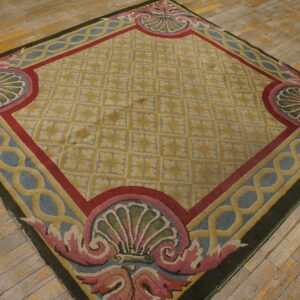 Gold diamond lattice rug with detailed pink and blue shell borders sits atop worn wooden floor planks.