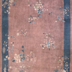 Rose-mauve field rug with a wide blue border featuring large floral vines and various decorative motifs.