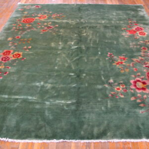 Deep green rug featuring trailing pink and red floral designs on a light wooden floor.