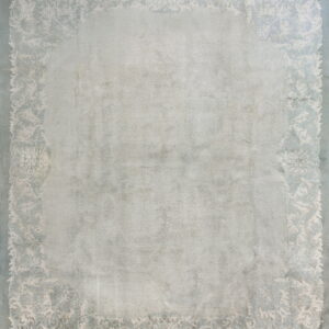 Light gray rug with a faded ornamental border pattern in cream and dusty blue.