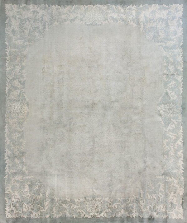 Light gray rug with a faded ornamental border pattern in cream and dusty blue.