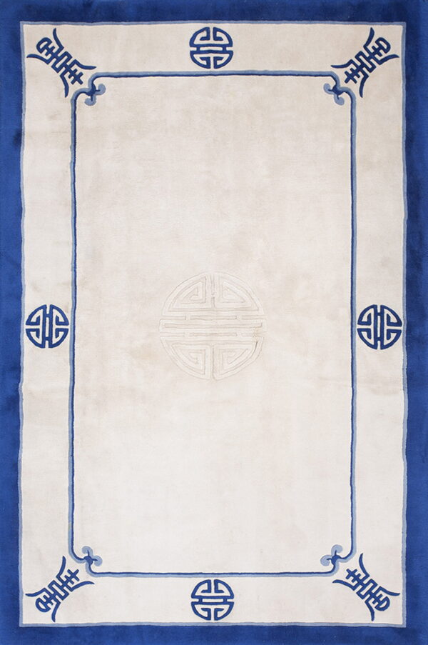 Minimalist vintage light blue and ivory white color open field chinese rug 1 A plush white rectangular rug featuring a wide blue border and dark blue traditional shou symbols along the edge.