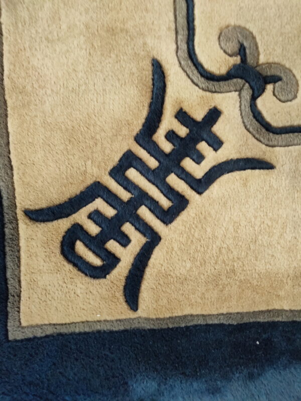 Minimalist vintage light blue and ivory white color open field chinese rug 2 Close-up of a rug featuring a tan field with dark blue and gray geometric and scrolling stylized patterns.