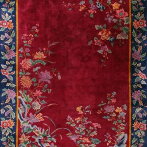Red field rug with colorful trailing flowers framed by a thick navy blue botanical border.