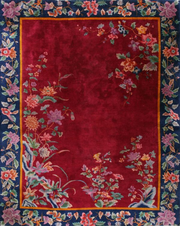 Red field rug with colorful trailing flowers framed by a thick navy blue botanical border.