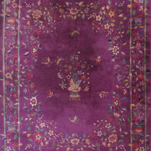 A deep purple rug with a multicolored floral and bird pattern framed by a green bamboo border.