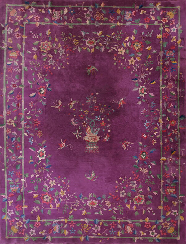 A deep purple rug with a multicolored floral and bird pattern framed by a green bamboo border.