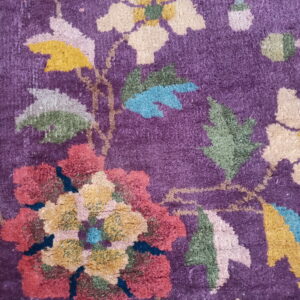 Textured purple rug surface with large stylized flowers in red, yellow, green, and cream colors.