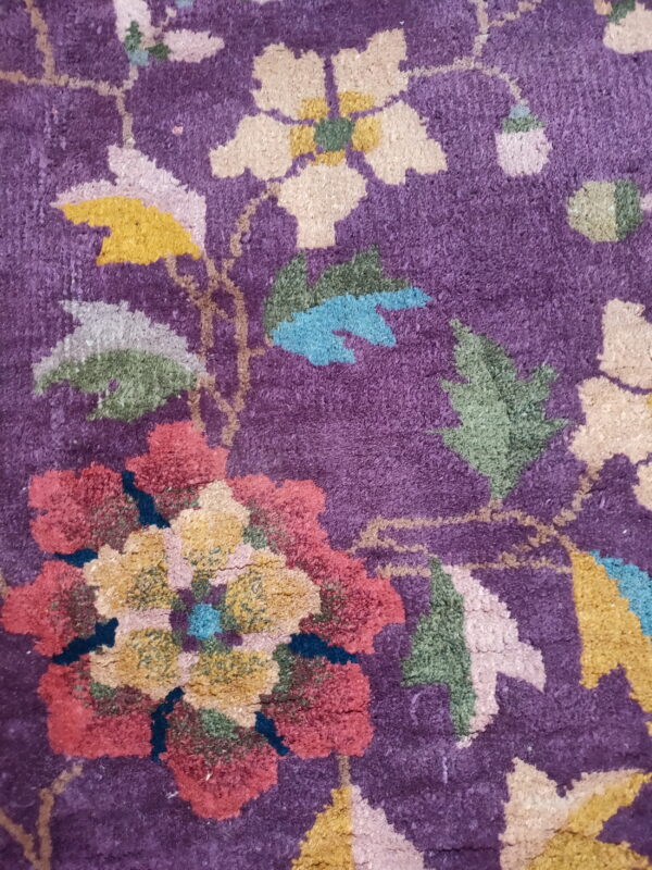 Textured purple rug surface with large stylized flowers in red, yellow, green, and cream colors.