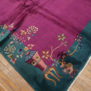 A plush magenta rug with a teal border and multi-colored floral patterns lies on a hardwood floor.