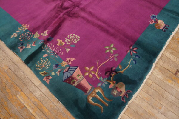 A plush magenta rug with a teal border and multi-colored floral patterns lies on a hardwood floor.