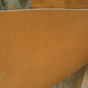 Close up of the ribbed terracotta rug backing resting on distressed brown hardwood planks.