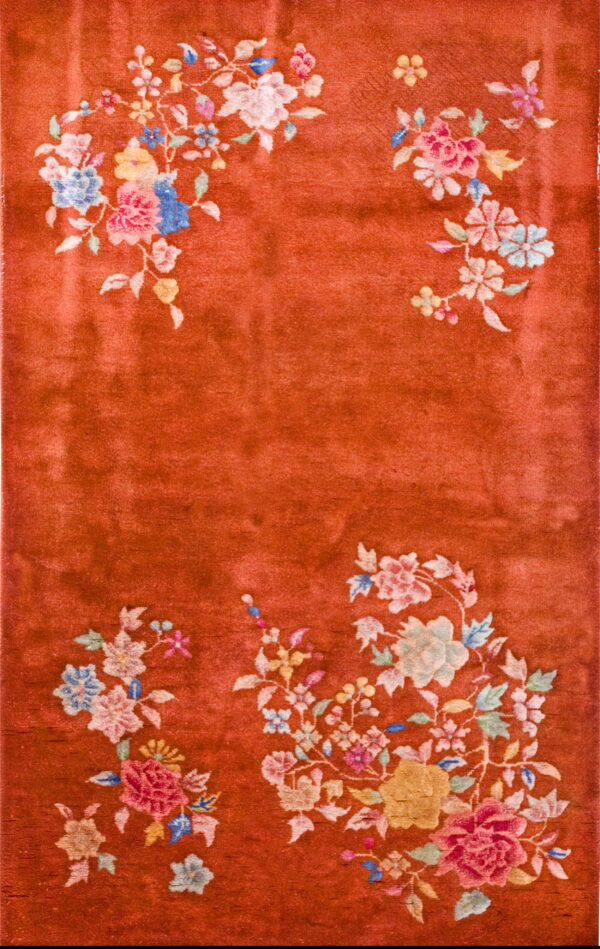 Plush rust rug with colorful floral sprays decorating the corners and edges.