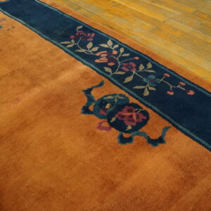Orange high-pile rug detail with a navy blue floral border visible on a golden wood floor.