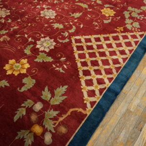 Burgundy rug detailed with yellow and white flowers, contrasting a blue border and rustic wooden floor.