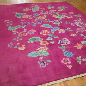 Magenta rug with a colorful scattered floral pattern, resting on hardwood flooring.
