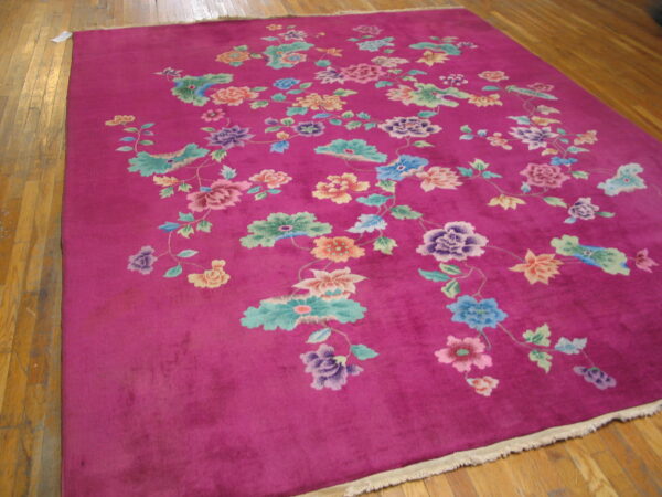 Magenta rug with a colorful scattered floral pattern, resting on hardwood flooring.