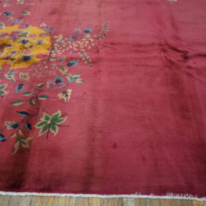 Plush magenta rug with an asymmetrical large-scale yellow, blue, and green floral design on wood floor.