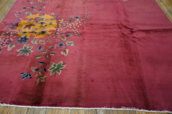 Plush magenta rug with an asymmetrical large-scale yellow, blue, and green floral design on wood floor.