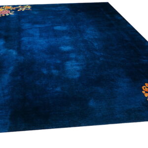 Dark blue high-pile rug featuring multicolored florals and an orange circular symbol in opposing corners.
