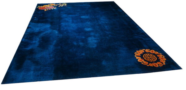 Dark blue high-pile rug featuring multicolored florals and an orange circular symbol in opposing corners.