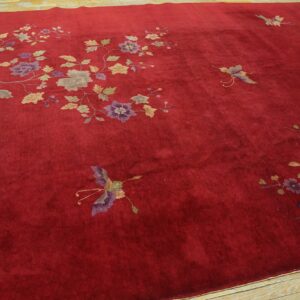 Velvety crimson rug with scattered flowering branches and butterflies rests on light wooden plank flooring.