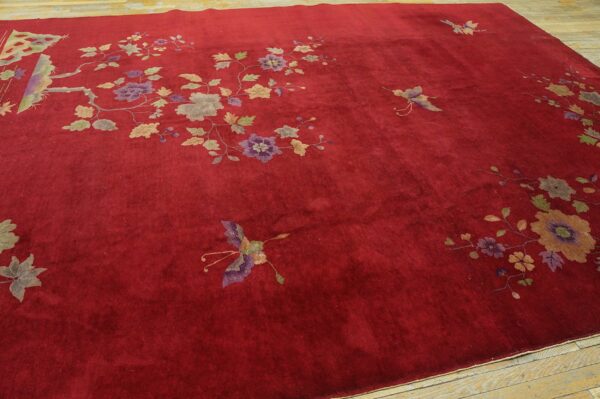 Velvety crimson rug with scattered flowering branches and butterflies rests on light wooden plank flooring.
