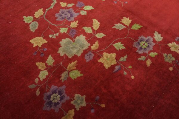 Deep red rug featuring an intricate scrolling floral vine pattern in shades of purple, gray, and olive green.