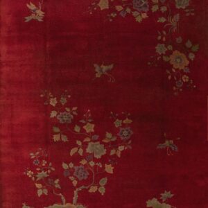 Deep crimson rug featuring an asymmetrical botanical pattern of gold, green, and purple flowers and butterflies.