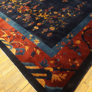 Plush navy rug displaying intricate floral branches and bordered by bands of rust red and teal blue.