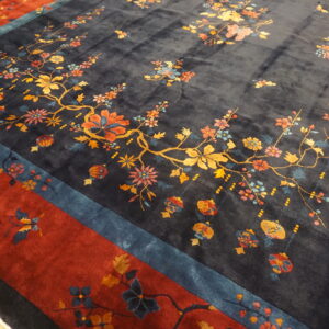 High-pile navy rug with colorful floral vines and lanterns, featuring teal and deep red borders on wood floor.