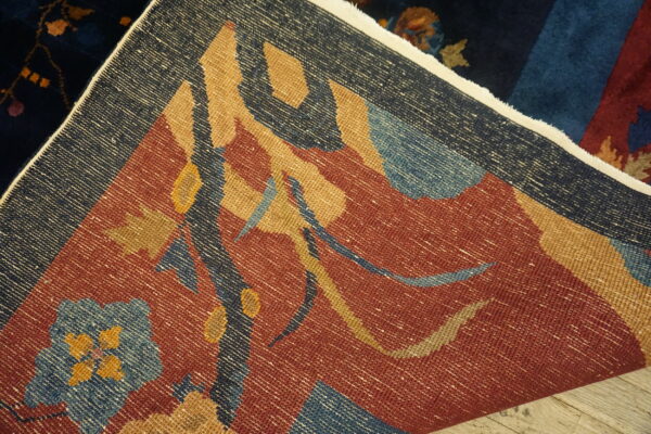 Flat-weave rug with rust and navy geometric patterns is folded over a dark blue plush rug.