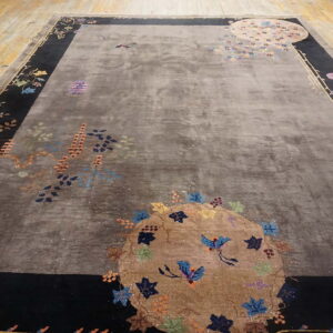 Gray high-pile rug with a detailed multicolored floral design and black border on a wood floor.