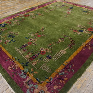 Bright green rug with colorful floral vines and vase motifs rests on distressed gray plank flooring.