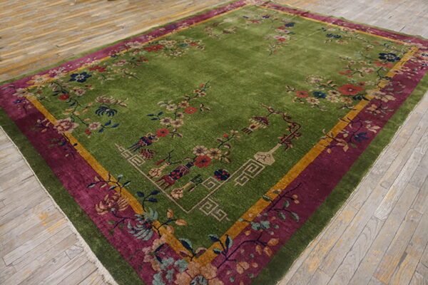 Bright green rug with colorful floral vines and vase motifs rests on distressed gray plank flooring.