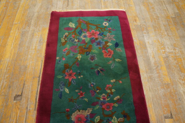 Teal runner with multi-colored blossoms and branches, framed by a burgundy border on distressed wood.