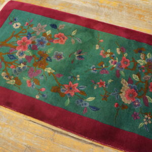 Teal runner with magenta border displays intricate pink, blue, and brown floral patterns on wood flooring.