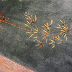 Deep green high-pile rug with colorful floral and bamboo patterns rests on worn wooden planks.