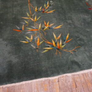 Velvety dark green rug with stylized colorful bamboo and flowers on rustic wood planks.