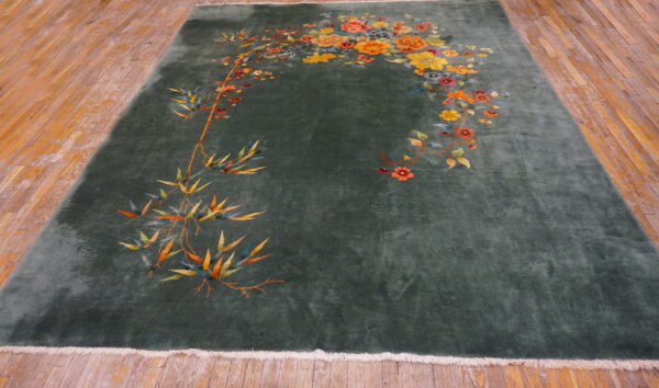 Dark green rug featuring vibrant orange and yellow bamboo and floral motifs displayed on light wood flooring.
