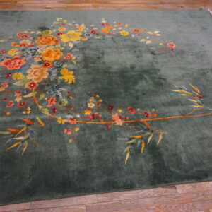 Plush sage green rug with colorful bamboo and floral patterns displayed on wood flooring.