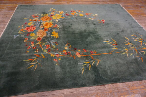 Plush sage green rug with colorful bamboo and floral patterns displayed on wood flooring.