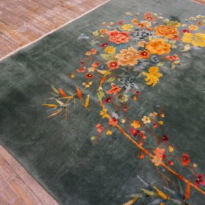 Deep green plush rug featuring sweeping yellow and orange floral branches on rustic hardwood flooring.