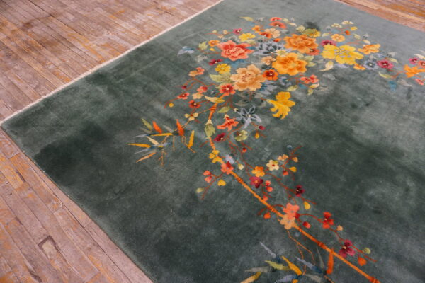 Deep green plush rug featuring sweeping yellow and orange floral branches on rustic hardwood flooring.